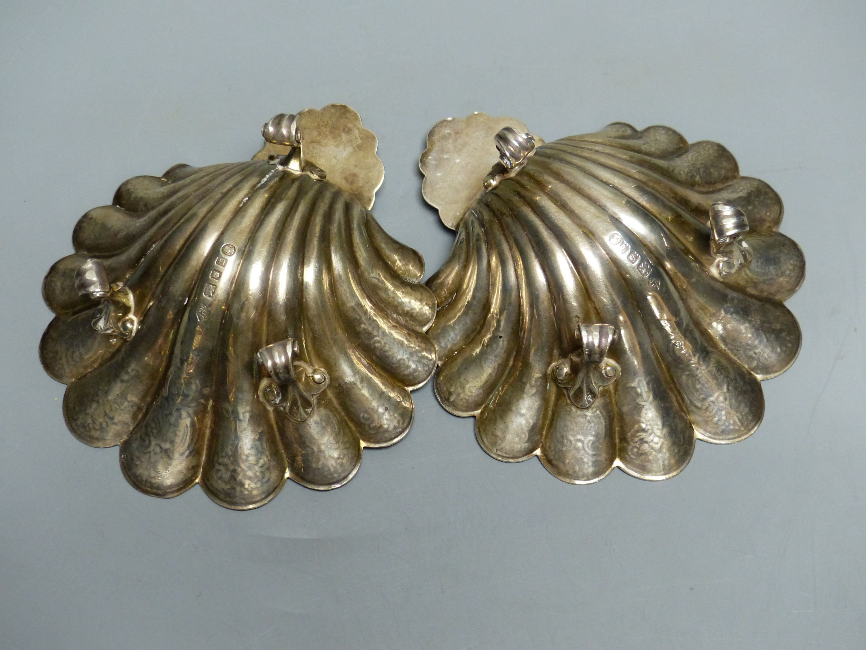 A pair of engraved scallop shell bon bon dishes on three scrolled feet, London 1934, 12.6cm, 9oz.